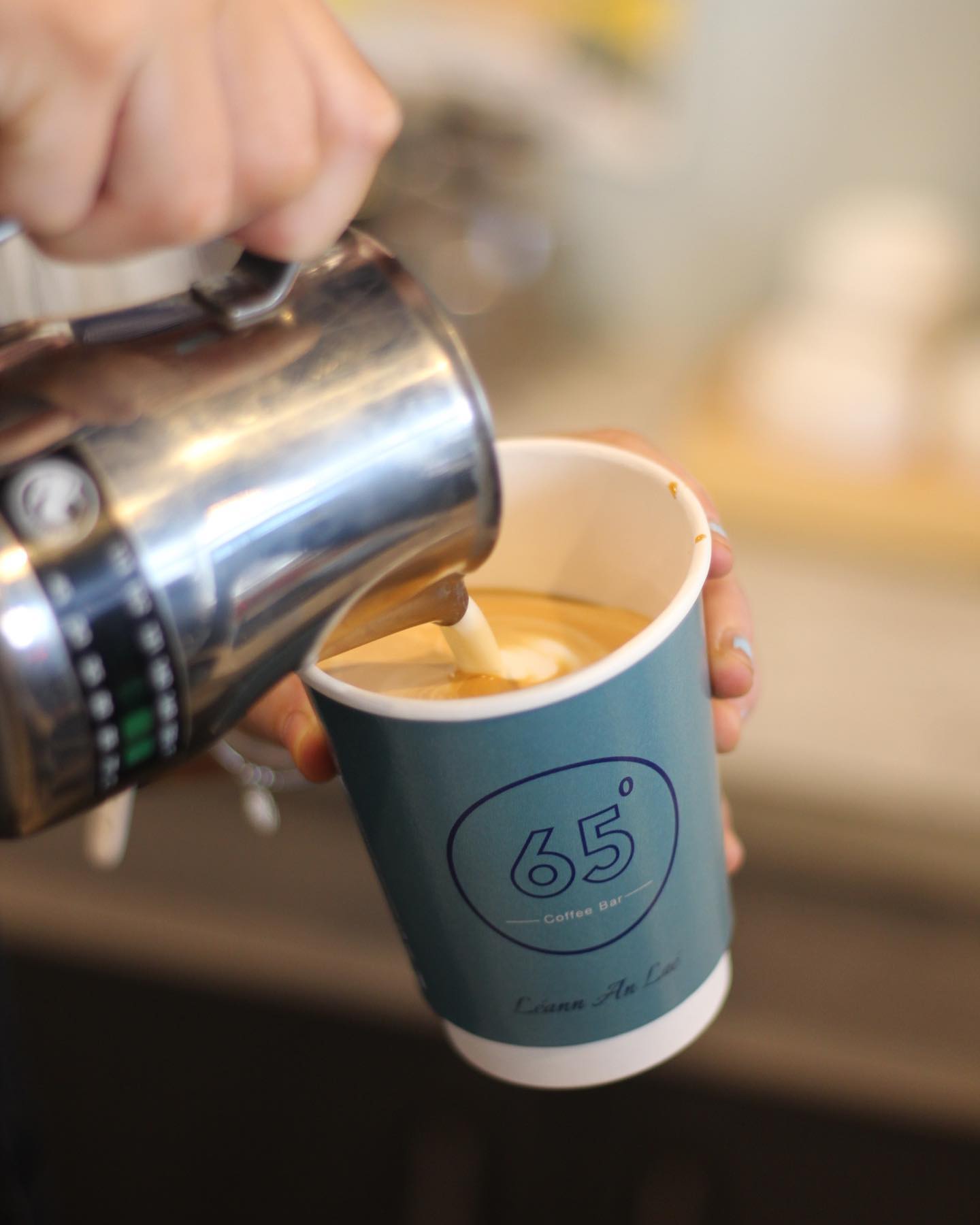 Barista carefully pouring steamed milk at 65 Degrees Coffee Bar